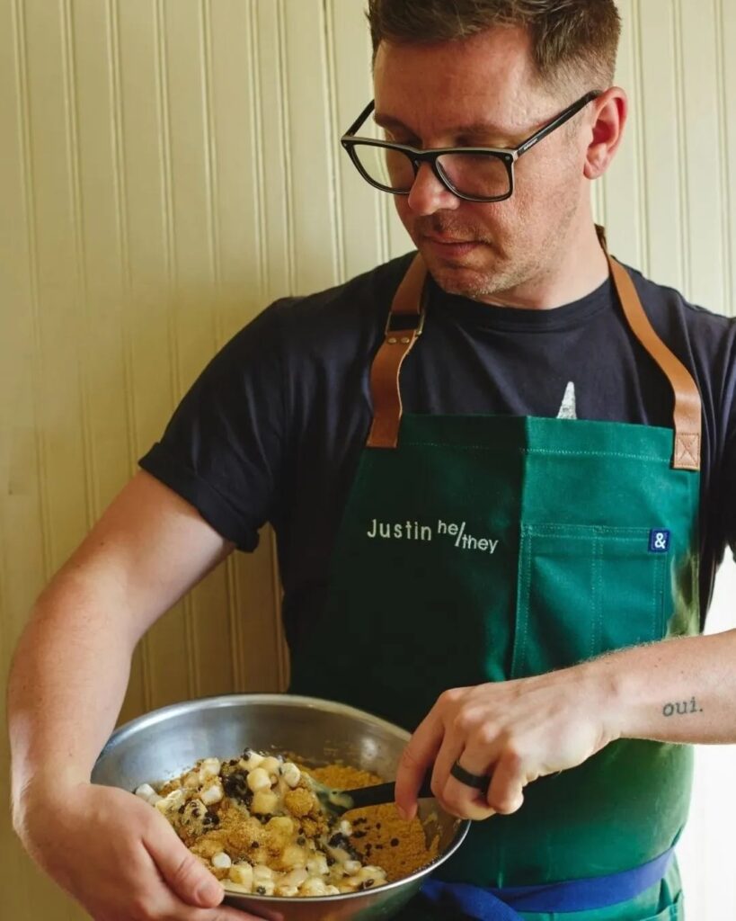 Justin wearing his apron and stirring a cookie mix in a silver bowl