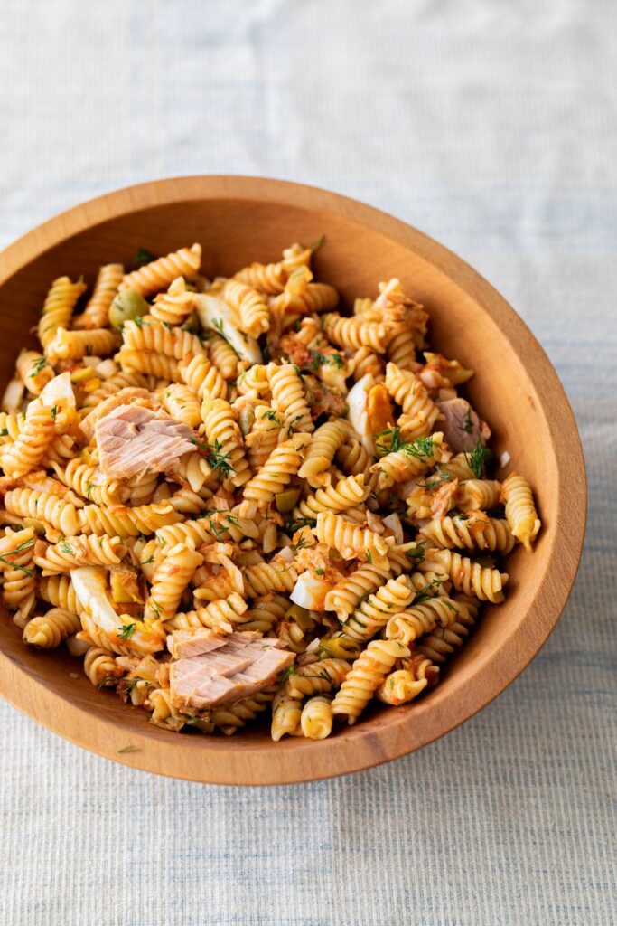 Fusilli pasta with tuna and tomato in a wooden bowl
