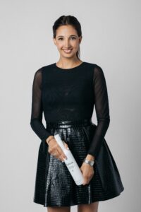 Katina Mountanos in a black dress holding a bottle of Kosterina olive oil