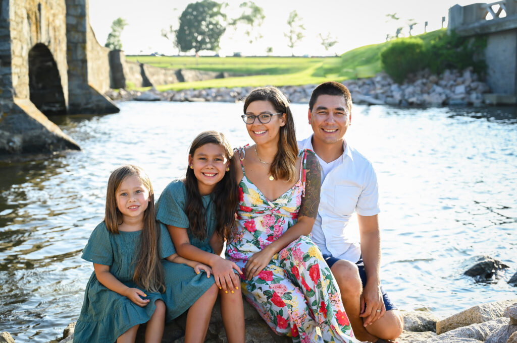 Kris, her husband and two young daughters sitting by a stream