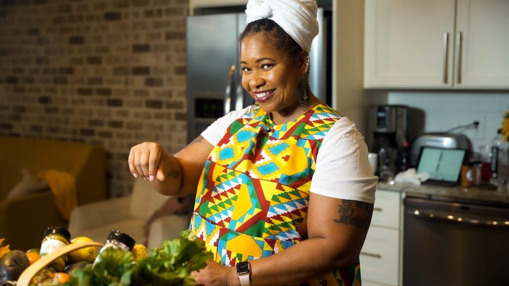 Chef Liesha McKinley-Barnett in a colorful apron in her kitchen