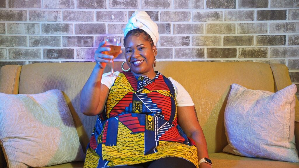 Chef Liesha McKinley-Barnett on a sofa raising a glass