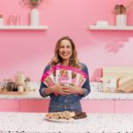 Loren Castle in a pink kitchen holding Sweet Loren's cookie dough packages