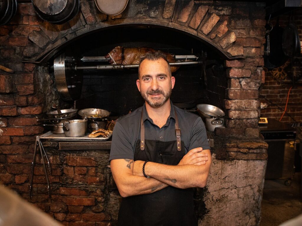 Marc Forgione standing in front of a brick oven