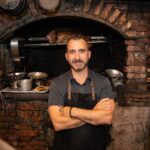 Marc Forgione standing in front of a brick oven
