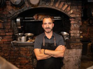 Marc Forgione standing in front of a brick oven
