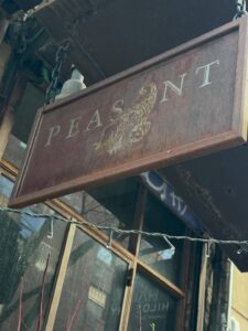 Peasant's restaurant sign in brown with white lettering and picture of a peasant