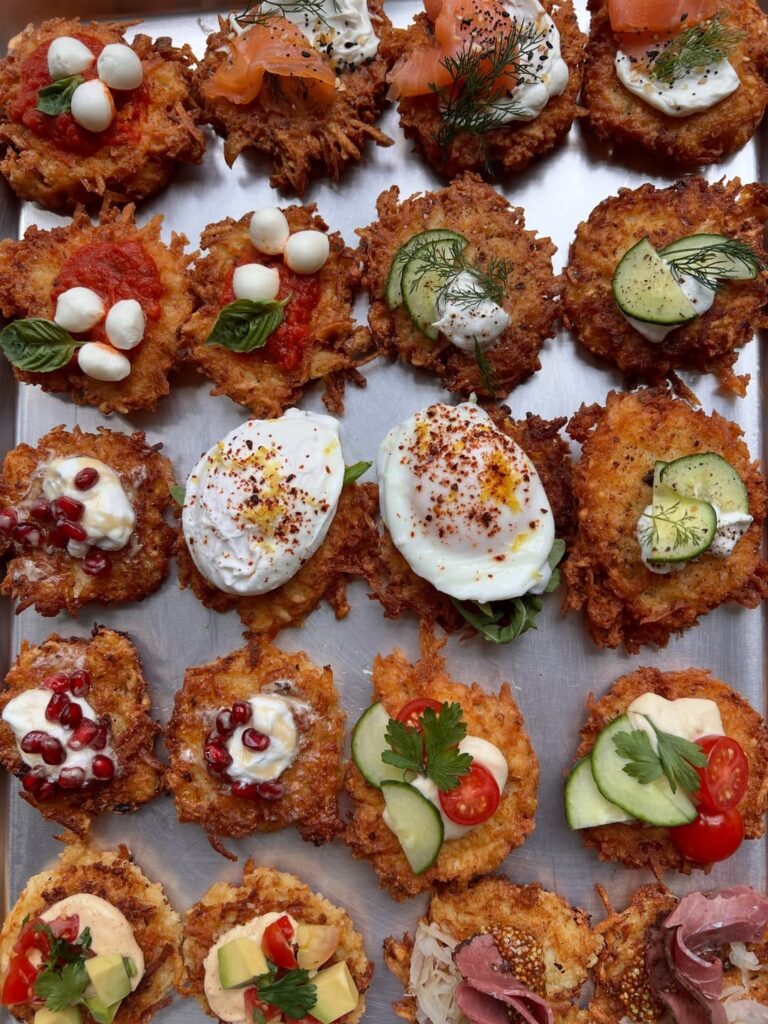 a silver sheet pan with variety of latke and toppings