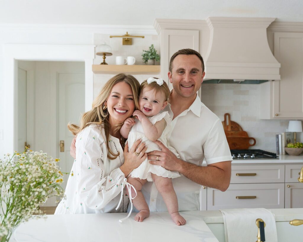 Michelle, her husband Aviv and daughter Zoe standing at the island in their white kitchen