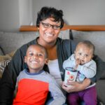Nicole Washington sitting on the couch with her kids on her lap