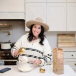 Rebecca Smith wearing a white and black striped sweater prepping food in her white kitchen