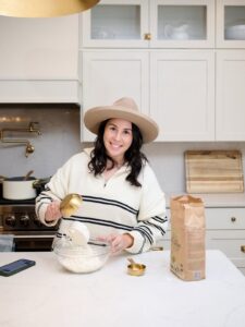 Rebecca Smith wearing a white and black striped sweater prepping food in her white kitchen