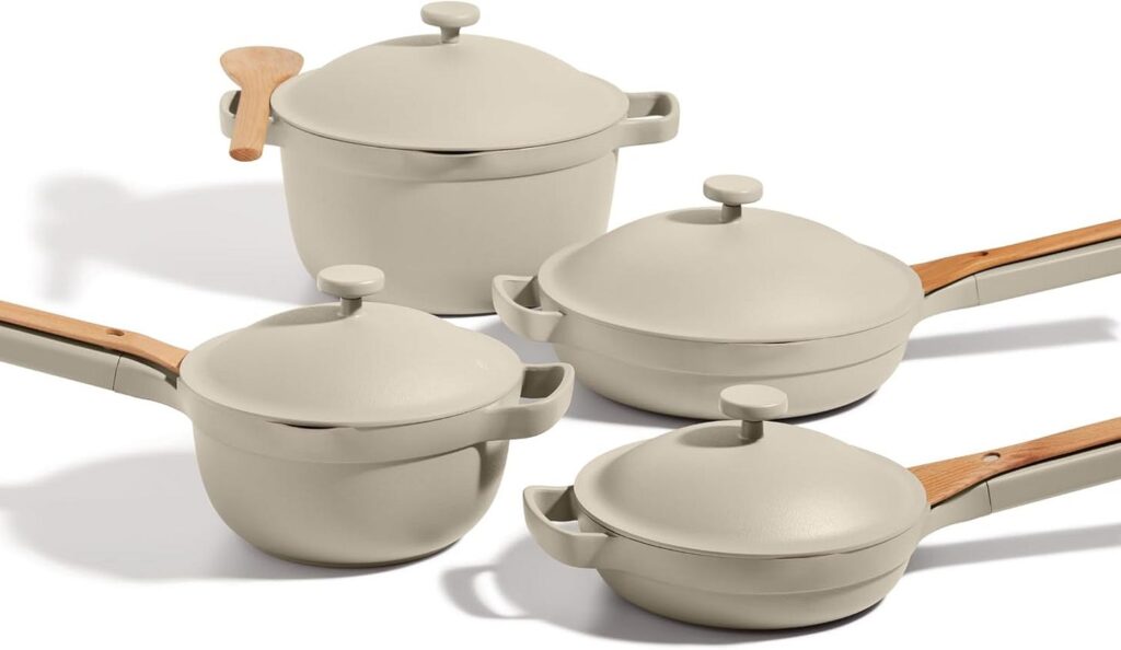 Set of cream-colored Our Place pots and pans with wooden handles