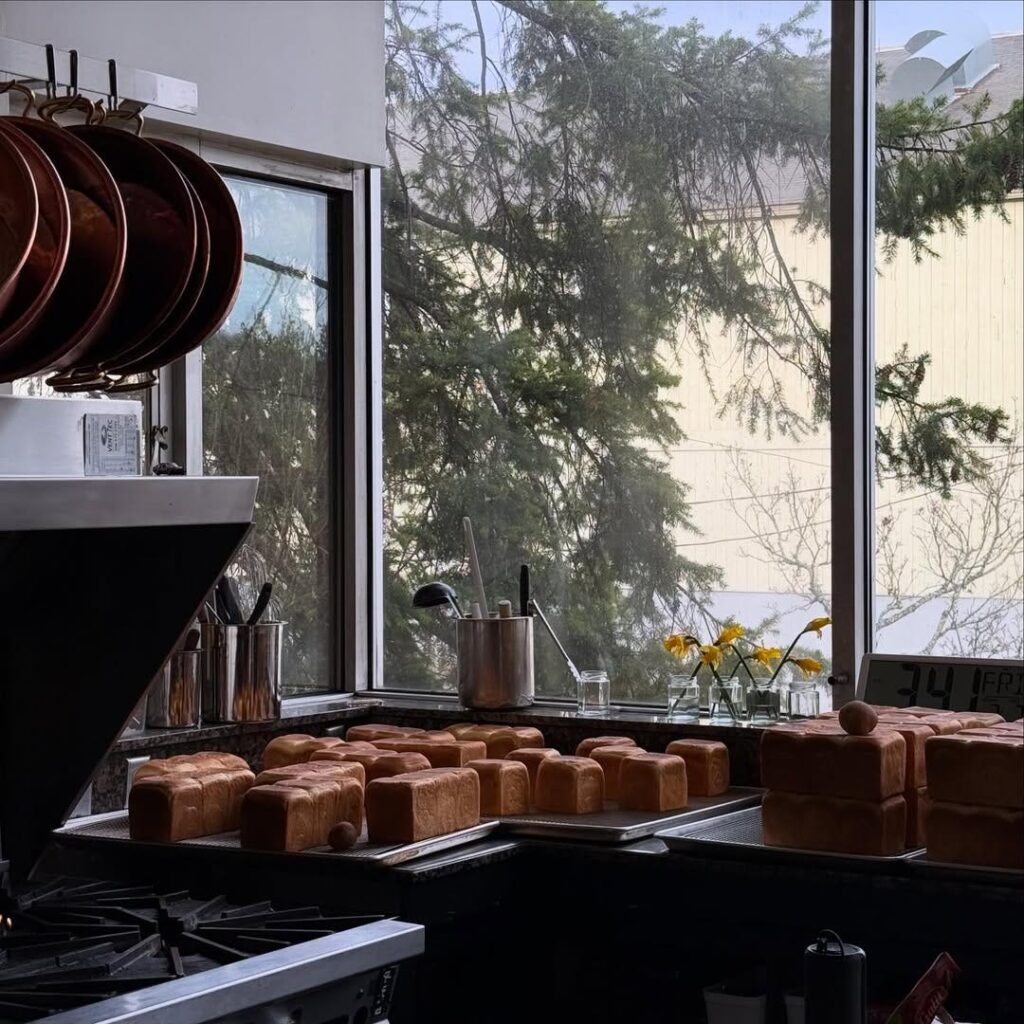 Loaves of shokupan bread in a kitchen beneath hanging copper pans