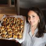 Shannon Sarna in a striped shirt holding a tray of chocolate croissants