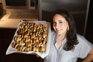 Shannon Sarna in a striped shirt holding a tray of chocolate croissants