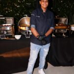 Chef in black coat standing in front of a silver buffet station