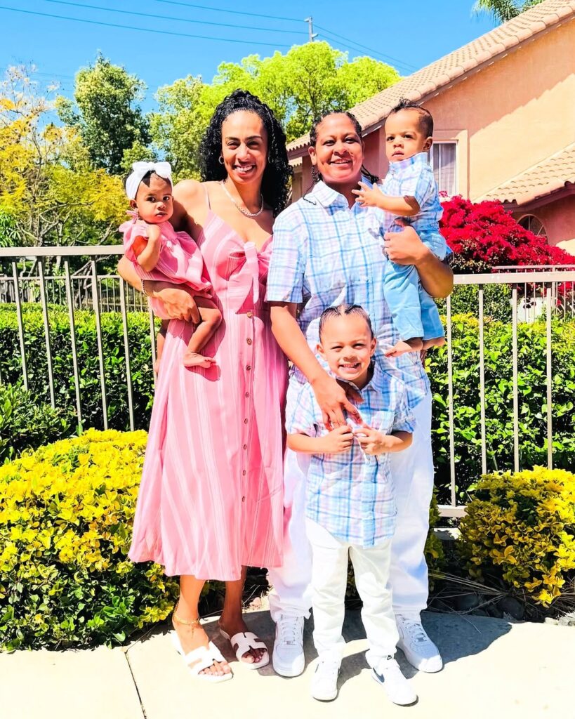 Chef Tasha stands smiling with her wife and 3 kids