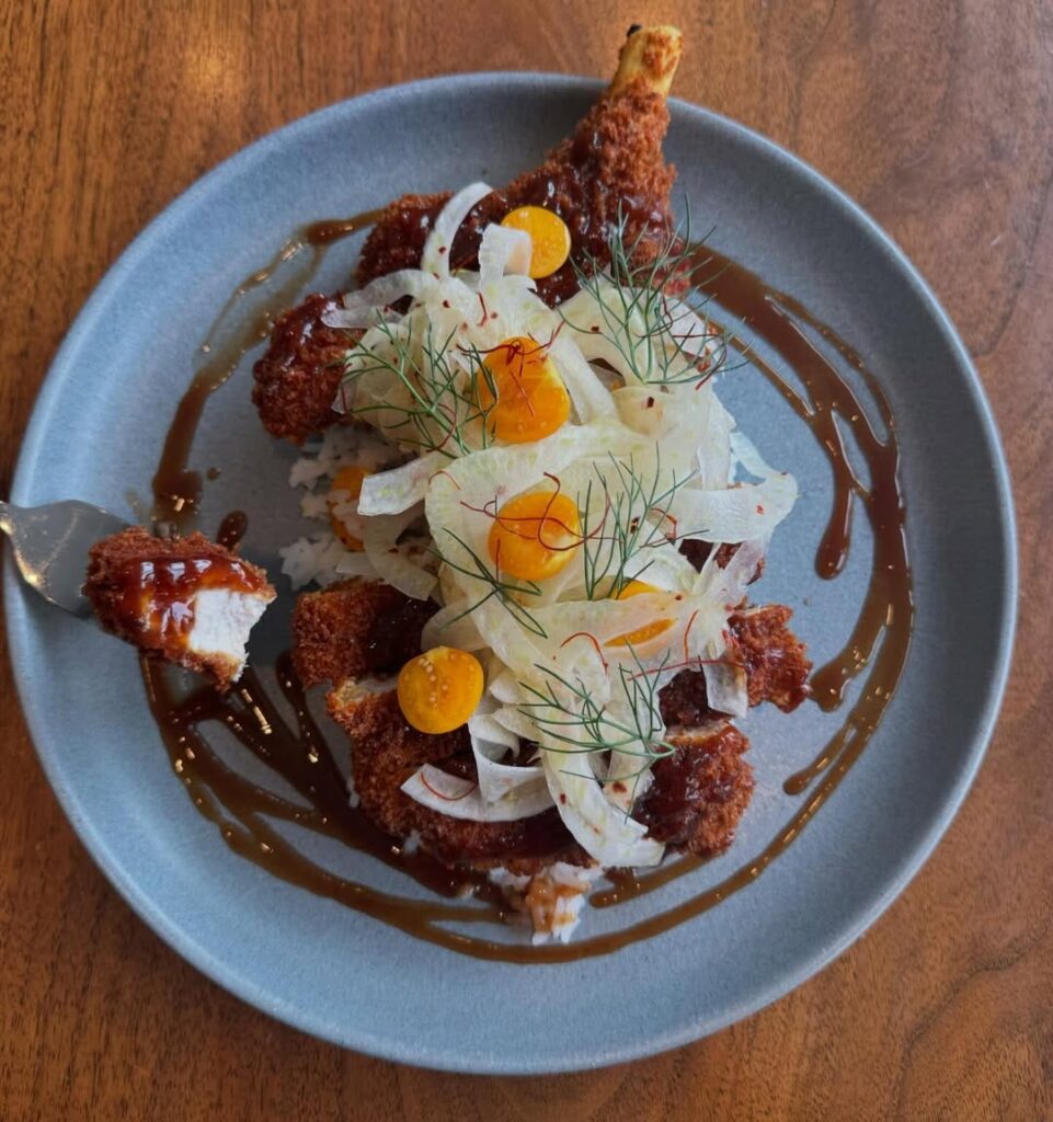 Crispy fried chicken plated with shaved fennel, citrus and a dark glaze