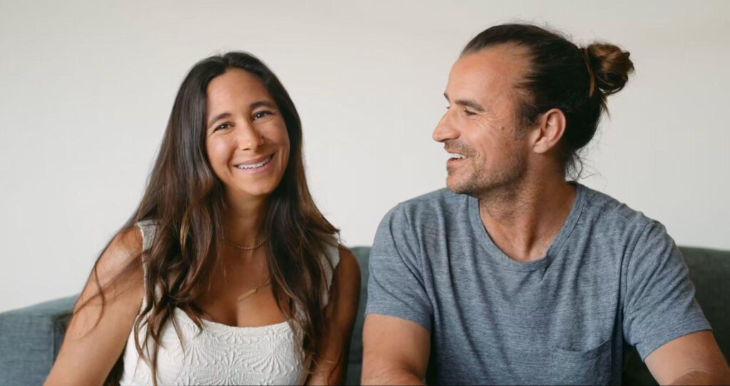 Torie Borrelli Hall and Eric Wolfinger smiling at each other, seated side by side